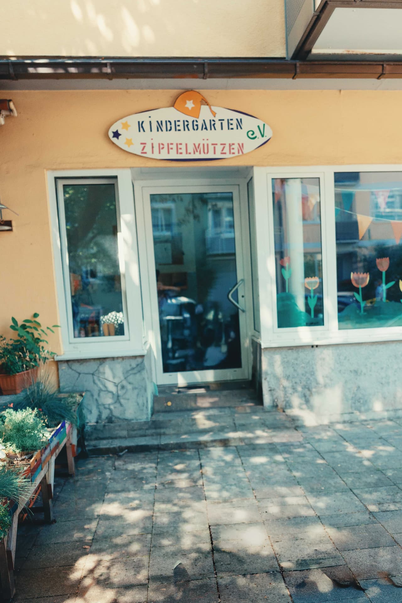 Eingang des Kindergartens Zipfelmützen e.V. mit buntem Schild über der Tür